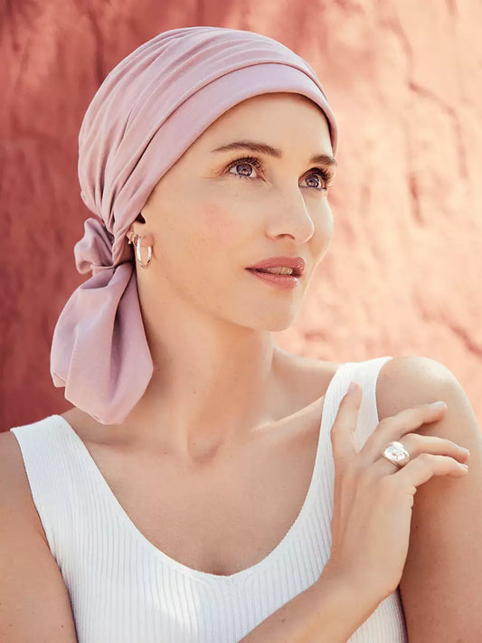 Turban femme Mila Woodrose, style et confort avec base ajustée et drapé élégant. Adapté aux femmes avec pelade ou alopécie. Bandeau semi-attaché pour créer un chignon sur le côté et maintenir volume et tenue naturelle